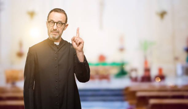 istock Priest religion man happy and surprised cheering expressing wow gesture pointing up 1041972422