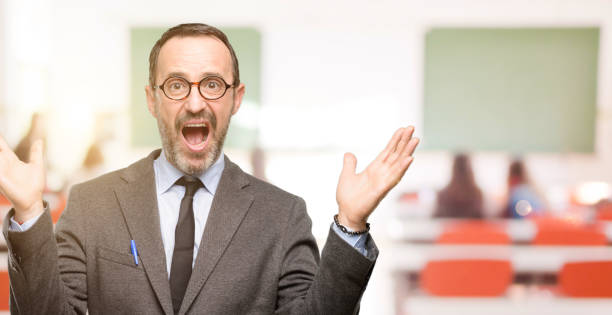 istock Teacher man using glasses happy and surprised cheering expressing wow gesture 1041972666