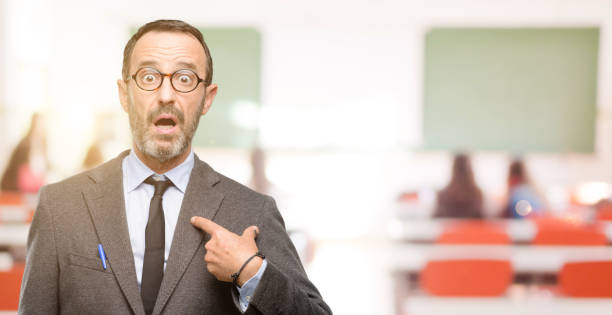 istock Teacher man using glasses happy and surprised cheering expressing wow gesture, pointing with finger 1041972712