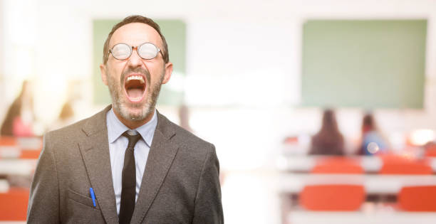 Teacher man using glasses stressful, terrified in panic, shouting exasperated and frustrated. Unpleasant gesture. Annoying work drives me crazy