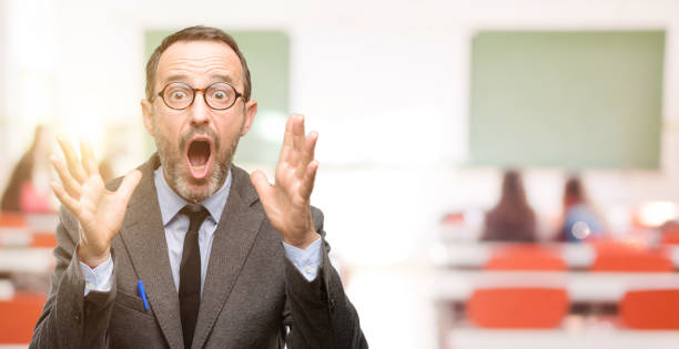 istock Teacher man using glasses stressful keeping hands on head, terrified in panic, shouting 1041972816