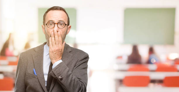 istock Teacher man using glasses covers mouth in shock, looks shy, expressing silence and mistake concepts, scared 1041972938