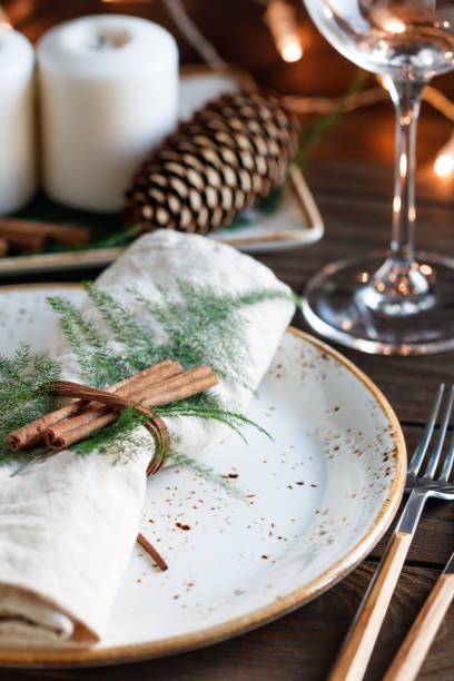 istock Thanksgiving table setting among white candles and cones. Decorated  linen napkin by cinnamon sticks. The concept of a festive dinner. 1041981998