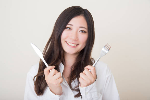 istock young asian woman with knife and fork 1041982750