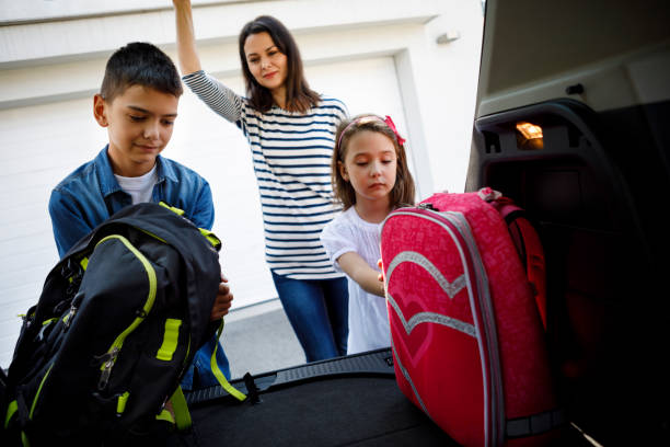 istock Mother and children loading school backpacks into car 1041984088