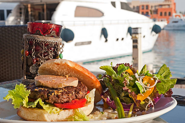 A mouthwatering hamburger served with crispy fries and a fresh salad on a white plate, evoking a sense of comfort and satisfaction.