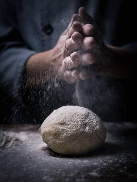 istock pastry chef hand sprinkling white flour over Raw Dough on kitchen table. 1041996638