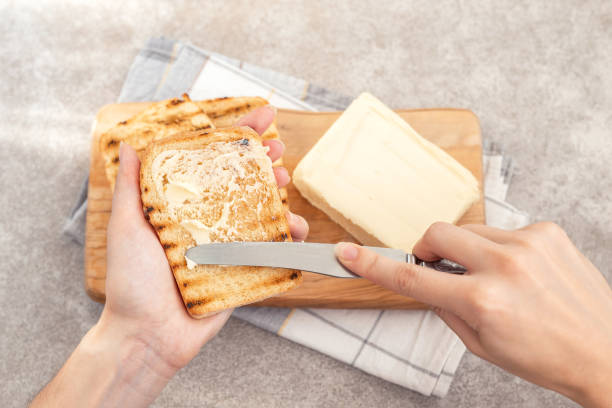 istock Female hand butters toasts for breakfast 1041997074