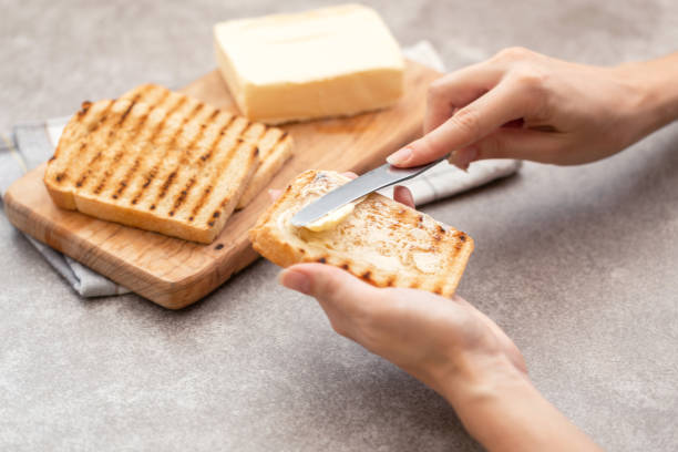Female hand butters toasts for breakfast