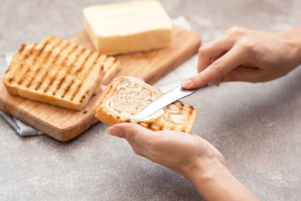 istock Female hand butters toasts for breakfast 1041997252