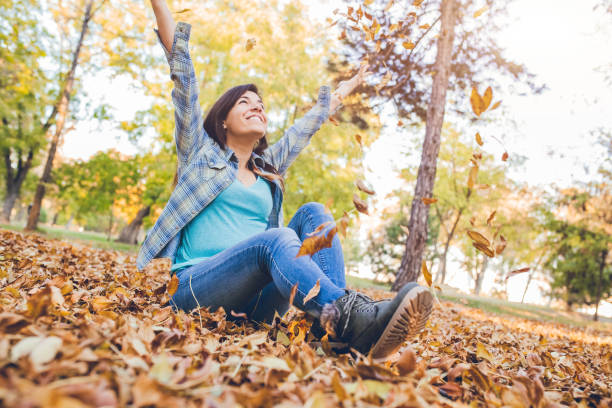 istock Woman throwing fallen autumn leaves 1042001830