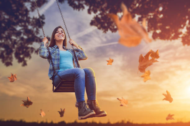 istock Woman on a swing among falling autumn leaves 1042002510