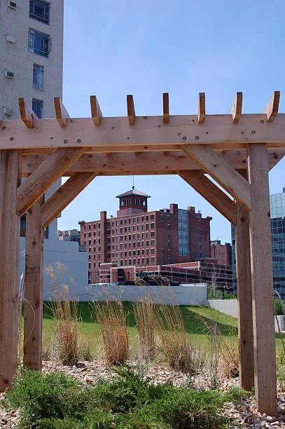 View of the back of the historic New York Life Building in Kansas City, Missouri, framed by a pergola in downtown green space. The building, which was the first multi-story highrise in Kansas City, was completed in 1890.