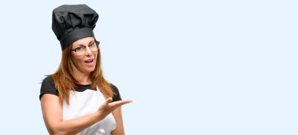 istock Middle age cook woman wearing chef apron holding something in empty hand 1042007658