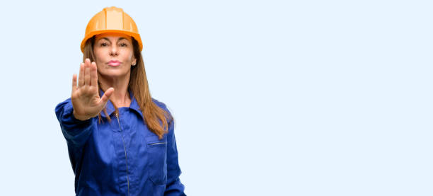 istock Engineer construction worker woman annoyed with bad attitude making stop sign with hand, saying no, expressing security, defense or restriction, maybe pushing 1042011232