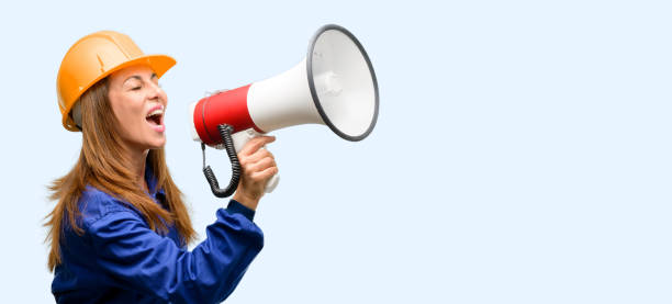 istock Engineer construction worker woman communicates shouting loud holding a megaphone, expressing success and positive concept, idea for marketing or sales 1042011636
