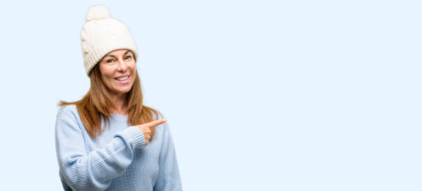 istock Middle age woman wearing wool winter cap pointing away side with finger 1042012008