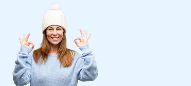 istock Middle age woman wearing wool winter cap doing ok sign gesture with both hands expressing meditation and relaxation 1042012102