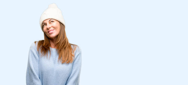 Middle age woman wearing wool winter cap thinking and looking up expressing doubt and wonder