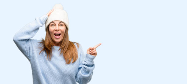istock Middle age woman wearing wool winter cap pointing away side with finger 1042012180