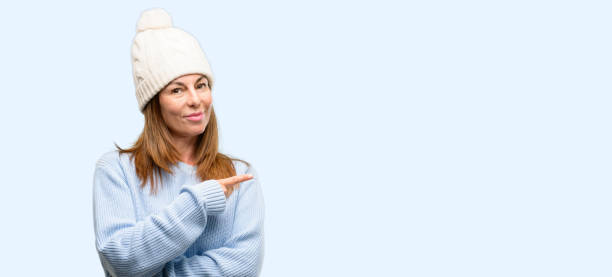 istock Middle age woman wearing wool winter cap pointing away side with finger 1042012296