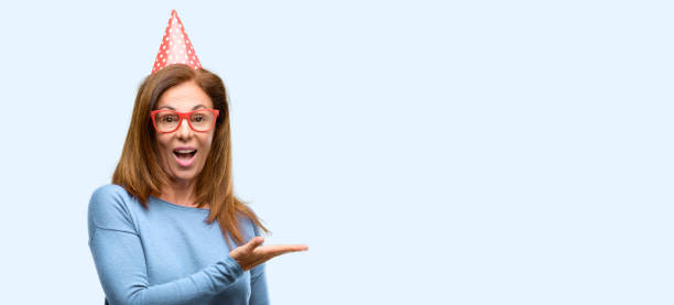 istock Middle age woman celebrates birthday holding something in empty hand 1042016328