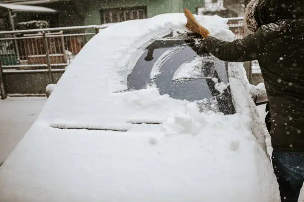 Photo of Man cleaning snow from car