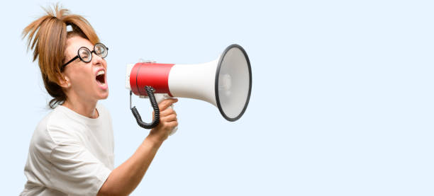 istock Crazy middle age woman wearing silly glasses communicates shouting loud holding a megaphone, expressing success and positive concept, idea for marketing or sales 1042017008