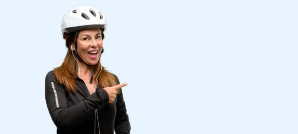 istock Middle age cyclist woman using earphones pointing away side with finger 1042020576
