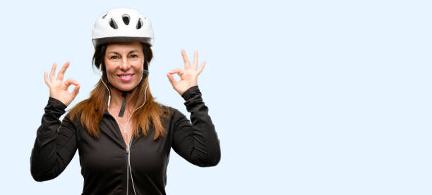 istock Middle age cyclist woman using earphones doing ok sign gesture with both hands expressing meditation and relaxation 1042020614