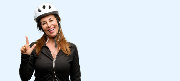 istock Middle age cyclist woman using earphones pointing away side with finger 1042020700