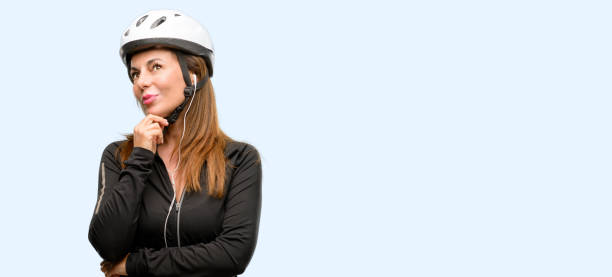istock Middle age cyclist woman using earphones thinking and looking up expressing doubt and wonder 1042020716
