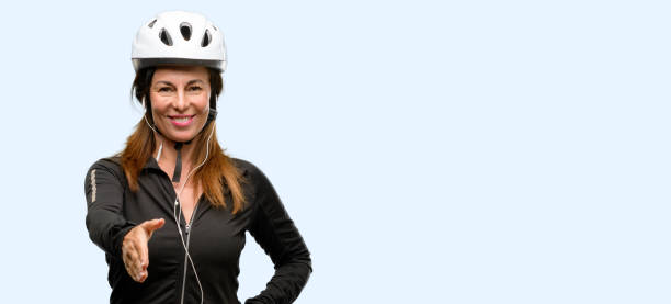 istock Middle age cyclist woman using earphones holds hands welcoming in handshake pose, expressing trust and success concept, greeting 1042020780