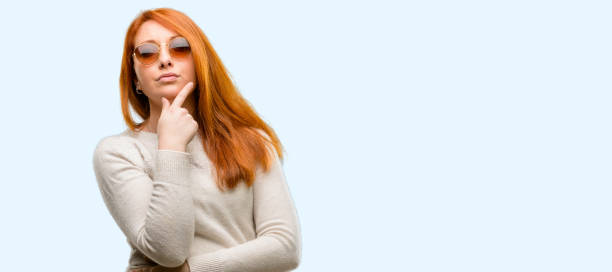 Beautiful young redhead woman doubt expression, confuse and wonder concept, uncertain future