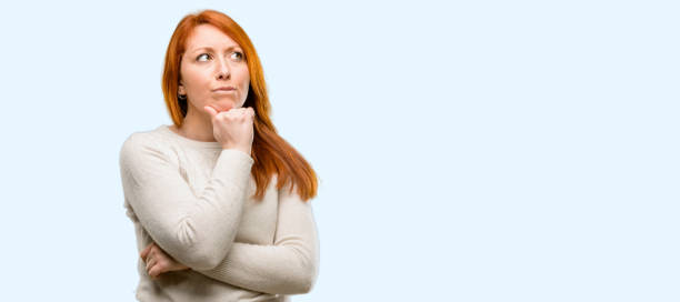 istock Beautiful young redhead woman thinking thoughtful with smart face 1042021436