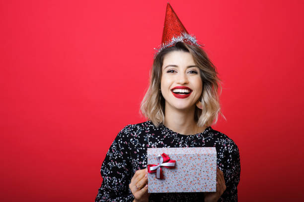 young woman holding christmas present and laughing - mirth imagens e fotografias de stock