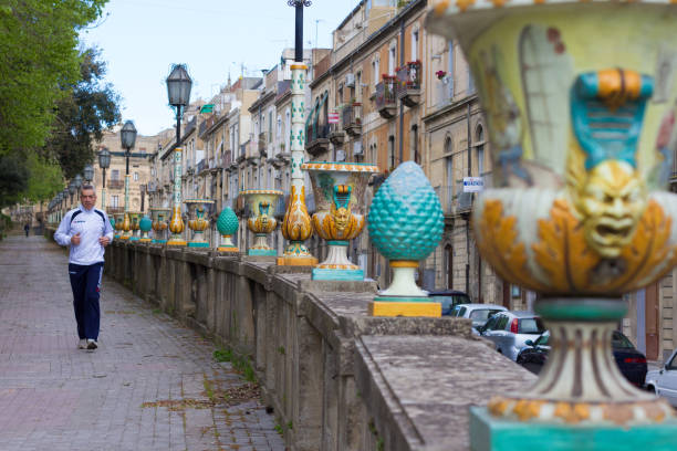 Caltagirone, Sicily: A man jogs through Caltagirone’s town park next to antique majolica pottery. Caltagirone is famous for the production of tiles and majolica and is part of the Val di Noto UNESCO World Heritage Site.