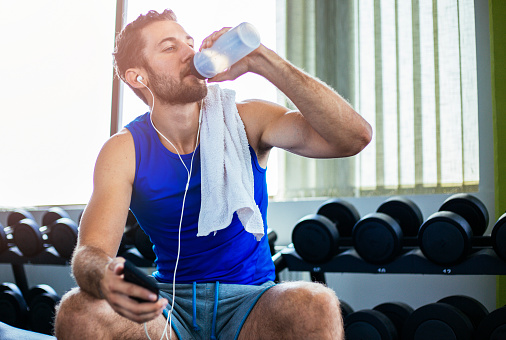 Fitness, gym and black man drinking water after workout or training for hydration, health or wellness. Strong, healthy and African athlete enjoying a beverage after intense exercise at sports center.