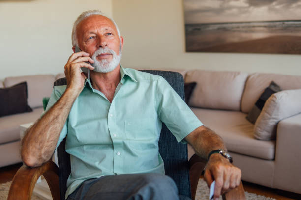 istock Old man with credit card talking on mobile phone 1042047436