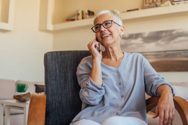 зрелая женщина разговаривает по мобильному телефону - women telephone senior adult on the phone стоковые фото и изображения