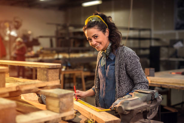 falegname professionista di mezza età che guarda la telecamera mentre prende misure di legno grezzo nel suo laboratorio. - carpentry workshop work tool craft foto e immagini stock