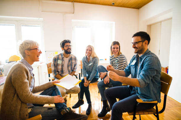 istock Group of people sitting in a circle on group therapy. One man is talking about his experience. 1042061698