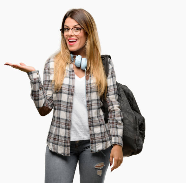 istock Young student woman with headphones and backpack holding something in empty hand 1042066054