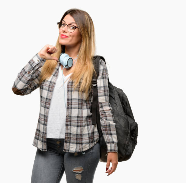 istock Young student woman with headphones and backpack proud, excited and arrogant, pointing with victory face 1042066310