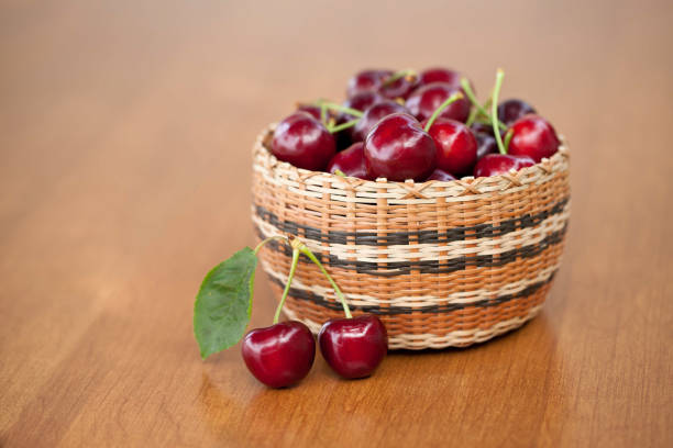 Red Ripe Cherries in a basket on a wood table