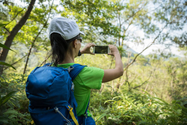 istock Backpacker taking picture with smartphone in sunny tropical rainforest 1042112372