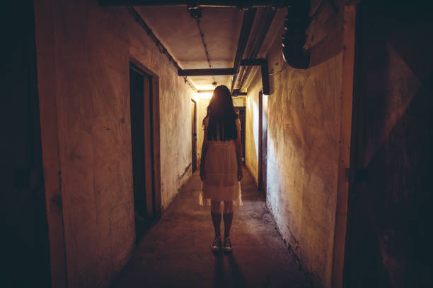 Little girl horror movie Scary girl in night gown in a dark basement hallway cosplay event stock pictures, royalty-free photos & images