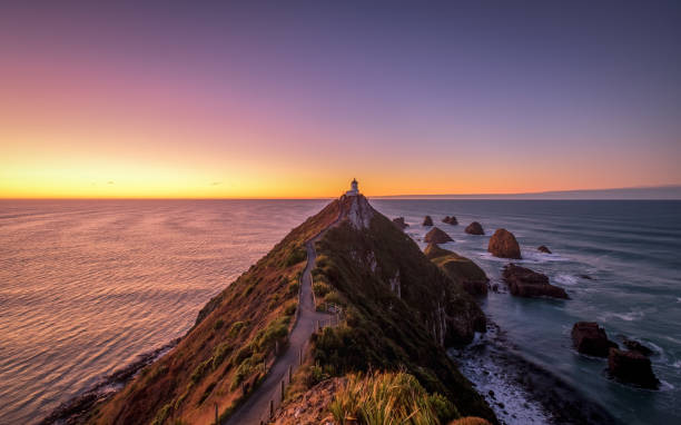 Scenic landscape of Nugget Point lighthouse, Otago, New Zealand Nugget Point is one of the most distinctive landforms along the Otago coast of New Zealand. It's a steep headland with a lighthouse and a scattering of rocky islets. This is extremely beautiful. dunedin new zealand stock pictures, royalty-free photos & images
