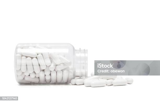 White Medicine Capsules Spill Out From Transparent Bottle Stock Photo - Download Image Now