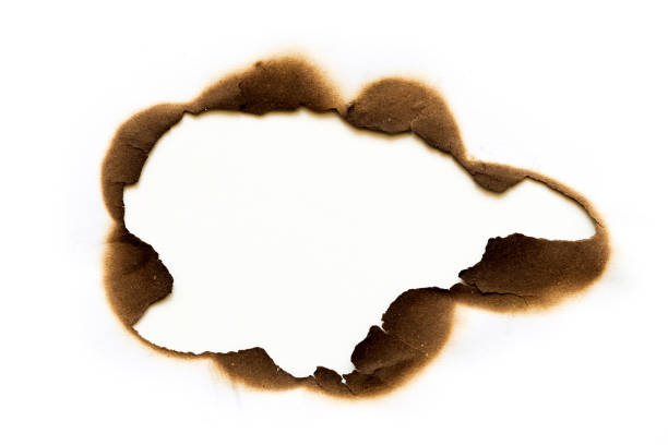 istock burned hole on piece of paper isolated on white background. 1042127758